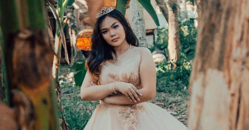 Debut - A Woman in Beige Gown with Tiara Standing Near Banana Trees