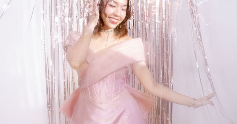 Debuts - A Woman in Pink Cocktail Dress Standing Beside Glittering Tinsel