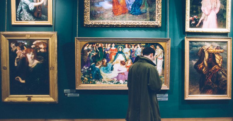 Artists - Man Standing in Front of Paintings